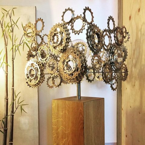 Un nuage d'engrenages flotte sur un socle en bois, une sculpture artisanale de Passion & Créations.