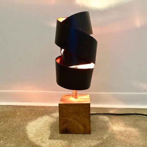 Une lampe artisanale avec un abat-jour noir et un socle en bois.
