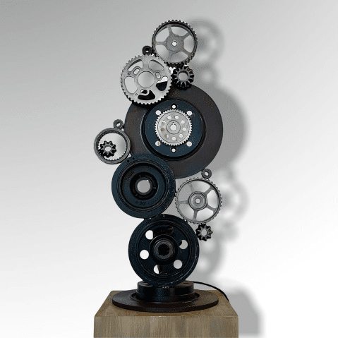 Sculpture avec des engrenages et disques de freins de voiture soudés les uns aux autres vu de face.