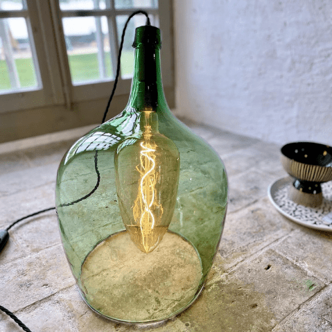 Lampe faite avec une dame Jeanne de couleur verte coupée en biais dont l'ampoule se trouve à l'intérieur. À retrouver chez Passion & Creations