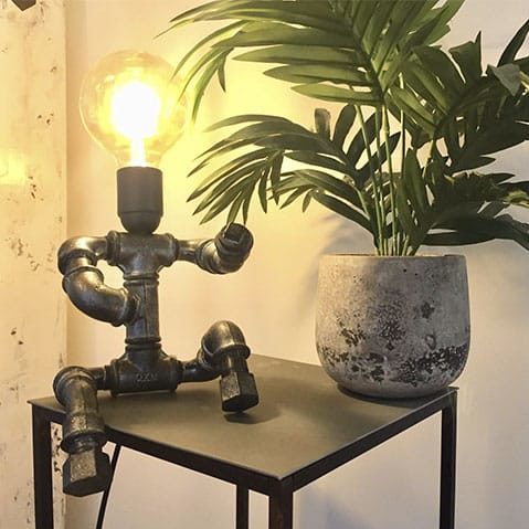 Une lampe artisanale en forme de bonhomme faite avec de la tuyauterie recyclée.