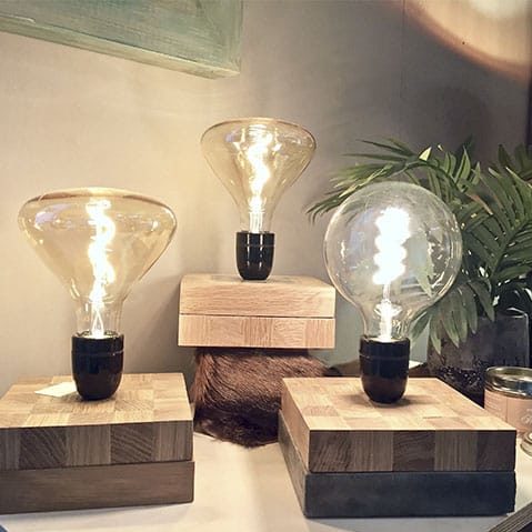 Trois lampes artisanales avec de belles ampoules et des socles en bois en damier illuminent la photo.
