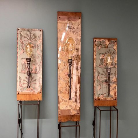 Des ampoules contre des fonds boisés composent trois lampes artisanales.