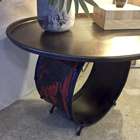 Une table rouge et noire composée d'un plateau circulaire et d'un pied en forme de tambour.