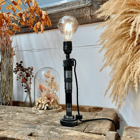 Arbre de boîte à vitesse transformé en lampe avec une ampoule allumée en forme de diamant.