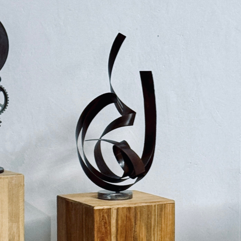 Sculpture abstraite Tout feu, tout flamme, formée de bandes d'acier courbées et entrelacées évoquant des flammes.